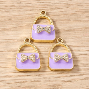 Detailed view of light purple enamel handbag charms with gold-toned bow and crystal inlay