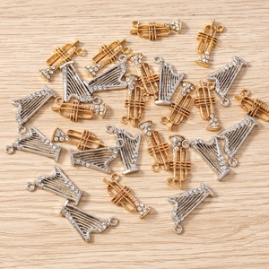 Détails macro de pendentifs trompette et harpe dorés et argentés avec strass pour bijoux DIY