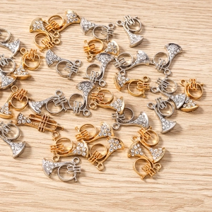 Détail macro de breloques de trompette or et argent avec strass blancs pour bijoux DIY