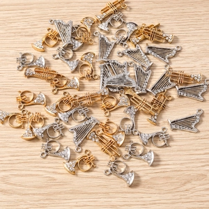 Détail macro de breloques trompette et harpe avec strass blancs pour bijoux artisanaux