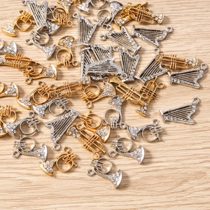Macro de pendentifs instruments en or et argent avec strass sur bois clair