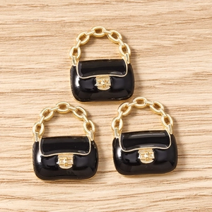 Détail macro de trois breloques sacs à main en émail noir avec anses dorées pour bijoux DIY