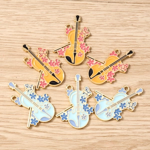 Detailed view of metal enamel violin pendants with floral patterns for jewelry making