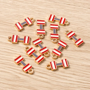 Vista macro de dijes de pesas con esmalte rojo y blanco para joyería artesanal