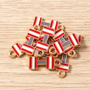 Detalle de dijes de pesas de esmalte con rayas rojas y blancas para joyería artesanal