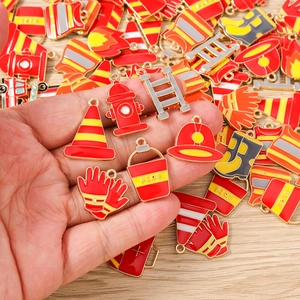 Macro detail of fire extinguisher charms and red enamel firefighter pendants for DIY jewelry