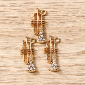 Vue macro de trois pendentifs trompette dorés avec strass blancs pour bijoux faits main