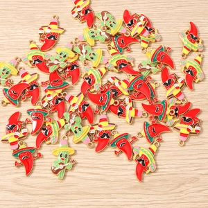 Detail showing enamel chili and cactus charms with Mexican style elements on wood background