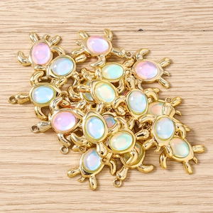 Détail macro de pendentifs tortue dorés avec incrustation d'opale pour la bijouterie DIY