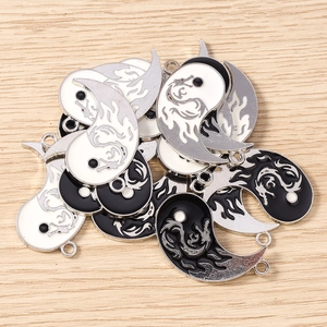 Detailed macro view of enamel Yin Yang charms with dragon patterns and dual connector rings