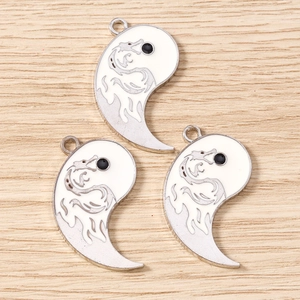 Macro detail of three silver dragon engraved Tai Chi pendants on light wood background
