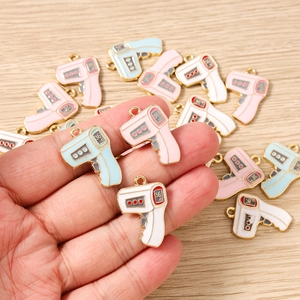 Close-up of thermometer pendants in pink, blue, and white enamel with gold trim for DIY charms