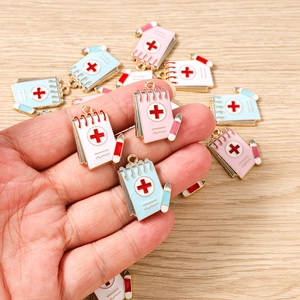 Detail of medical theme enamel notepad charms with red cross for DIY jewelry making