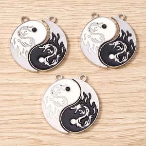Detailed macro view of silver Chinese Yin Yang dragon pendants with black and white enamel finish