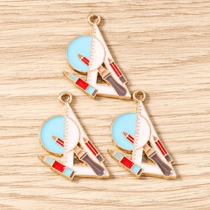 Détail de breloques émaillées avec règle et crayon pour la création de bijoux DIY