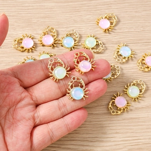 Macro detail of gold crab charms with colorful opal beads for DIY jewelry making and crafts