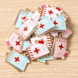 Macro detail of notebook charms with red cross medical symbols for DIY jewelry making