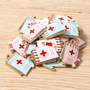 Macro detail of enamel notepad charms with medical red cross for DIY jewelry making