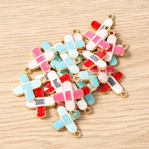 Detail of cross-shaped bandage enamel charms with metal loops for DIY jewelry making