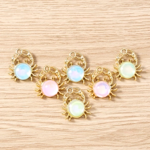 Macro view of colorful crab jewelry pendants on light wood background for DIY