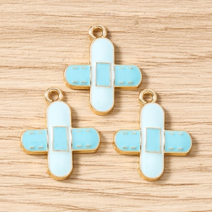 Macro shot of bandage shaped alloy charms in light blue and white for DIY jewelry making