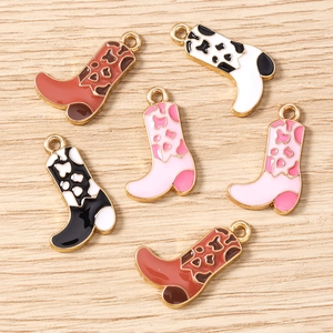 Detail showing colorful cowboy boot pendants with enamel animal prints on wood surface