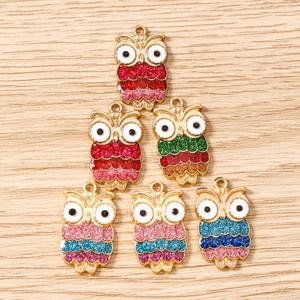 Detalle macro de dijes de búho con purpurina para la creación de joyas y manualidades DIY
