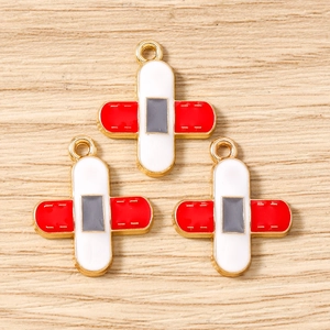 Three cross-shaped alloy enamel pendants on wood background for DIY jewelry making