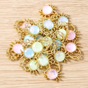 Macro detail of sun-shaped gold plated alloy charms with colorful iridescent cabochons