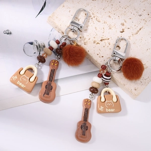 Brown tassel keychain with guitar pendant, plush pom pom and bear motif charm accessory