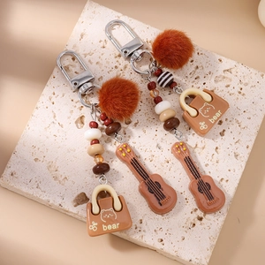 Close-up of tassel beaded keychain with plush ball and guitar bag charms on stone