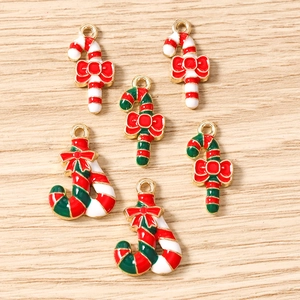 Macro detail of red and green enamel candy cane charms with festive gold trim and bows