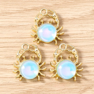 Detailed macro view of golden crab pendants with iridescent blue opal stones on wood surface