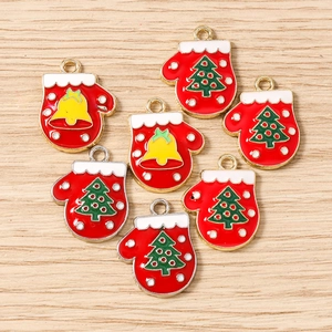 Macro view of red enamel Christmas mitten charms with gold trim on wooden background
