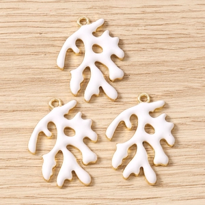 Gedetailleerde macro-opname van witte emaille koraalhangers met gouden randen voor DIY-sieraden