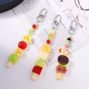 Porte-clés de fruits en résine avec breloques fraise et dessert sur fond blanc élégant