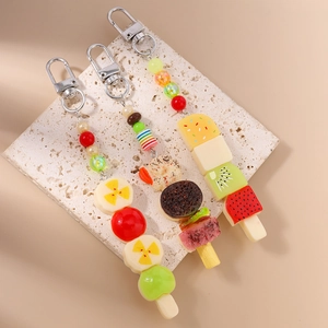 Vue détaillée de porte-clés réalistes en forme de brochettes de fruits sur socle