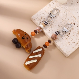 Detail of creative croissant and baguette keychains with decorative beads and silver clasp