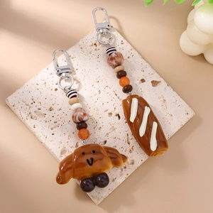 Detailed close-up of realistic faux croissant and bread keychain with colorful beads