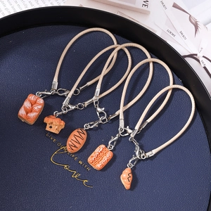 Five pieces of creative faux bread phone straps including croissant and toast shapes