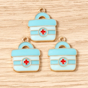 Dettaglio macro di tre ciondoli kit medico azzurri con croce rossa per gioielli fai-da-te