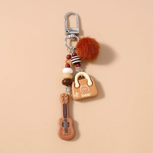 Detail of beaded keychain with brown faux fur pom pom and mini guitar charm ornament