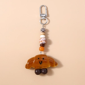 Detail of cute caramel croissant keychain with colorful beads and silver metal carabiner