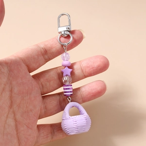 Detail of a purple beaded keychain with star beads and a small woven basket pendant