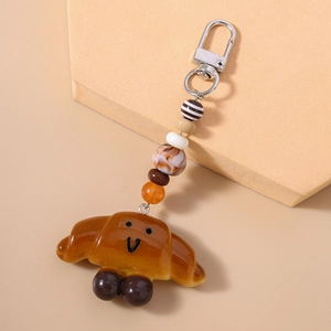 Detail of cute croissant keychain with smiley face and multi-color beaded strap with silver clasp