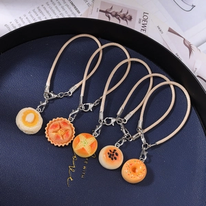 Five realistic artificial bread and donut charms with ropes on a blue display plate