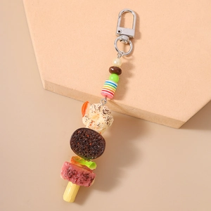 Détail d'un porte-clés créatif en forme de brochette de fruits avec des breloques réalistes