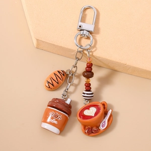 Detail of coffee cup keychain with latte art and bread charms on silver metal ring