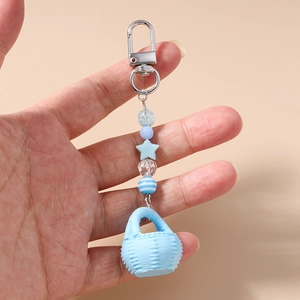 Detail of beaded keychain featuring a blue woven basket charm and star-shaped beads