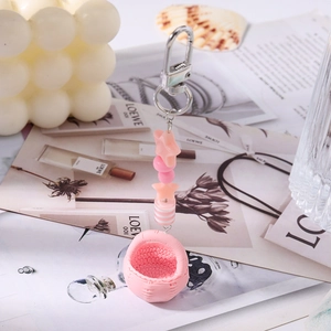 Detail of pink beaded keychain with stars and a small woven basket charm on a metal clasp